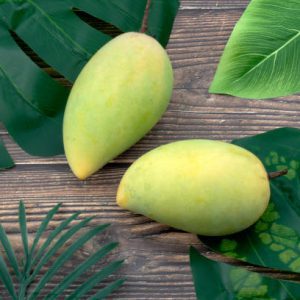 Mangos on table and green leafs top view